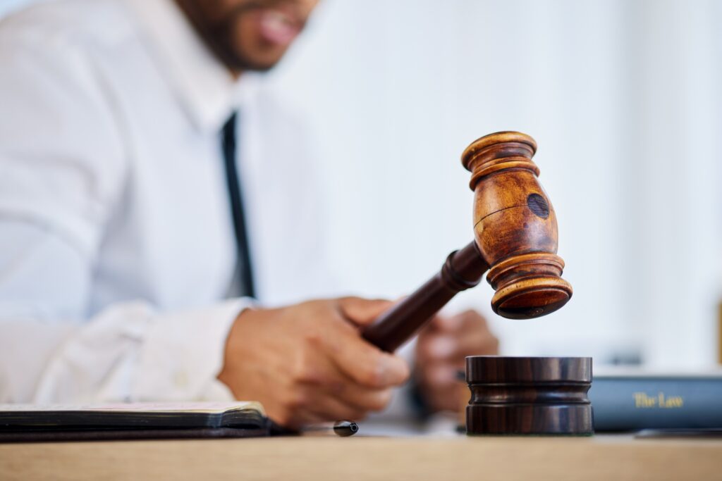 Hand, gavel and a man judge in court for order during a verdict in a criminal case or trial closeup